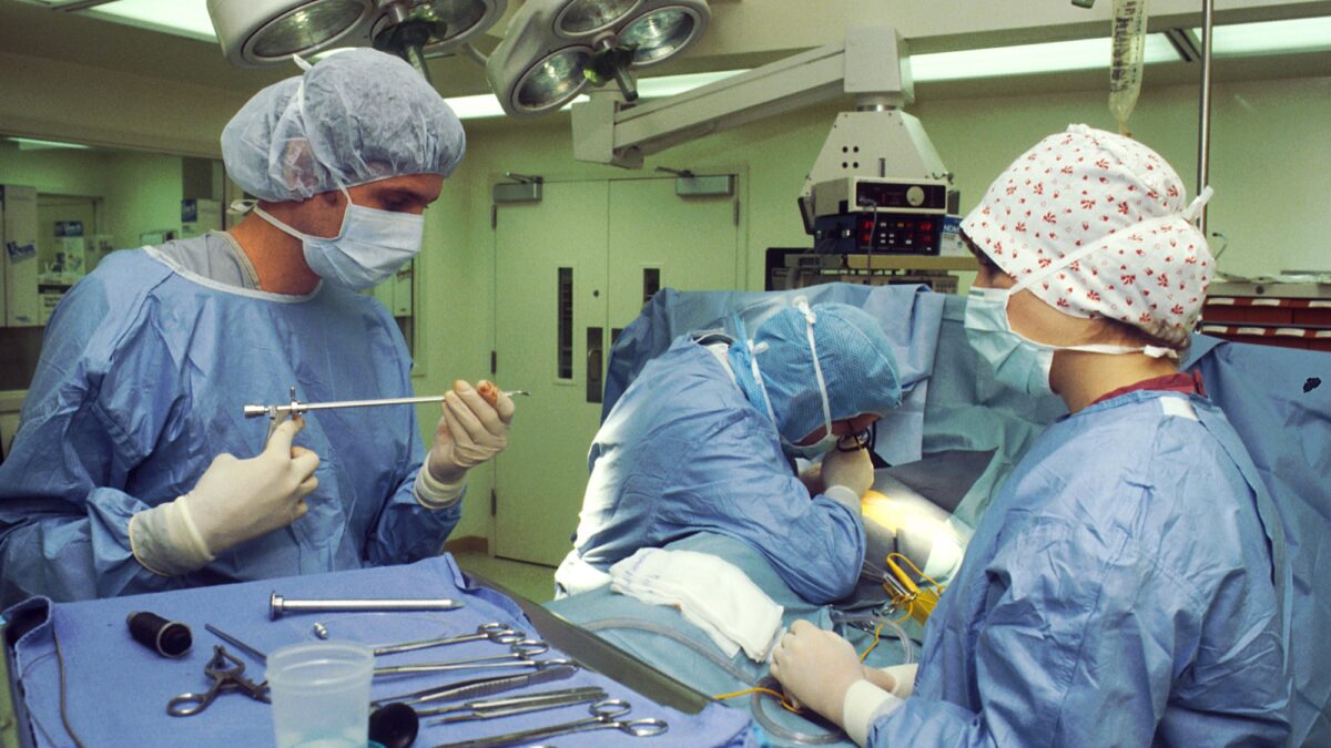 Equipe de cirurgiões e enfermeira durante procedimento em centro cirúrgico