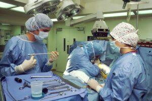 Equipe de cirurgiões e enfermeira durante procedimento em centro cirúrgico