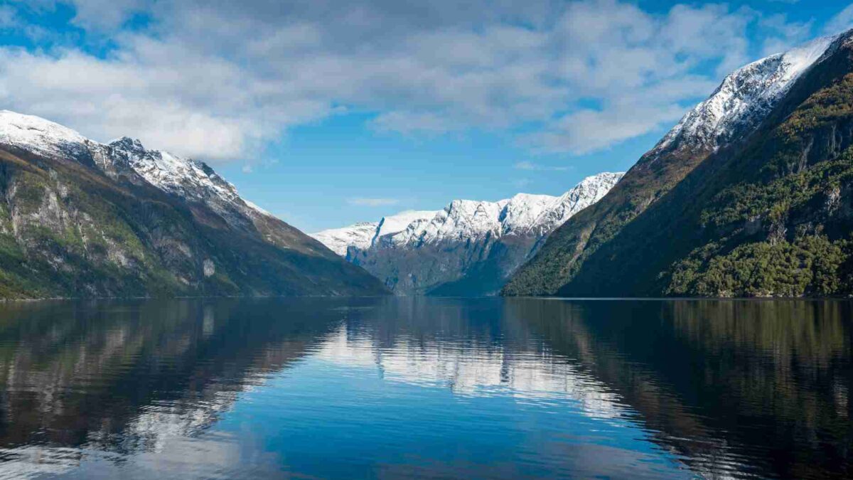 Fjord estreita com água agitada entre encostas rochosas cobertas de neve