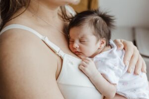 Amamentação e sono do bebê: recém-nascido dormindo durante a amamentação, representando o estudo japonês sobre duração do sono.