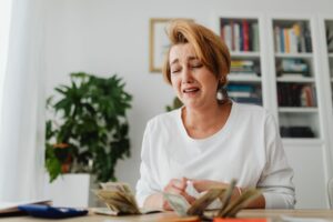 Idosa preocupada com contas, representando como dificuldades financeiras aceleram o envelhecimento cerebral.