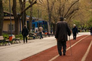 Idosa caminhando rapidamente em parque, representando o conceito de super movers e saúde cerebral.