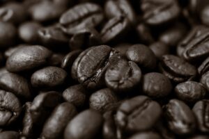Grãos de café torrados ao lado de um frasco de laboratório, simbolizando pesquisa que mostra como o café protege o envelhecimento ao ativar mecanismos celulares.
