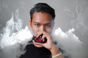Jovem adulto utilizando cigarro eletrônico durante teste de esforço em cicloergômetro, representando estudo que mostra como o vape reduz fôlego e a função vascular.