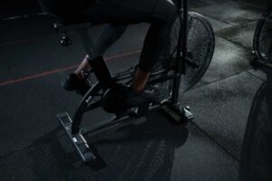 Ciclista em treino intervalado de sprint em bicicleta ergométrica; intensidade do exercício altera proteínas do sangue.