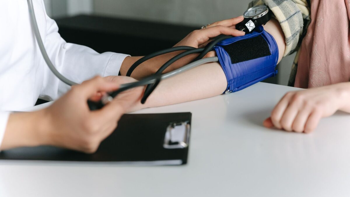Médico mede pressão arterial de paciente para avaliar risco de demência na meia-idade