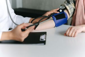 Médico mede pressão arterial de paciente para avaliar risco de demência na meia-idade