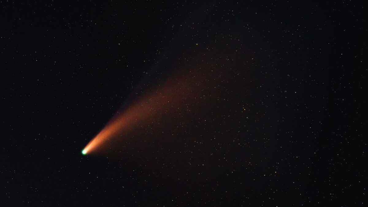 Cometa brilhante com longa cauda luminosa atravessando um céu noturno estrelado